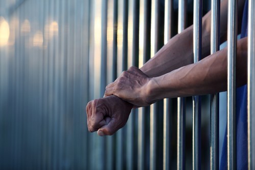 Inmates with arms extending out of a jail cell - misdemeanor probation in Colorado can allow defendants to avoid jail
