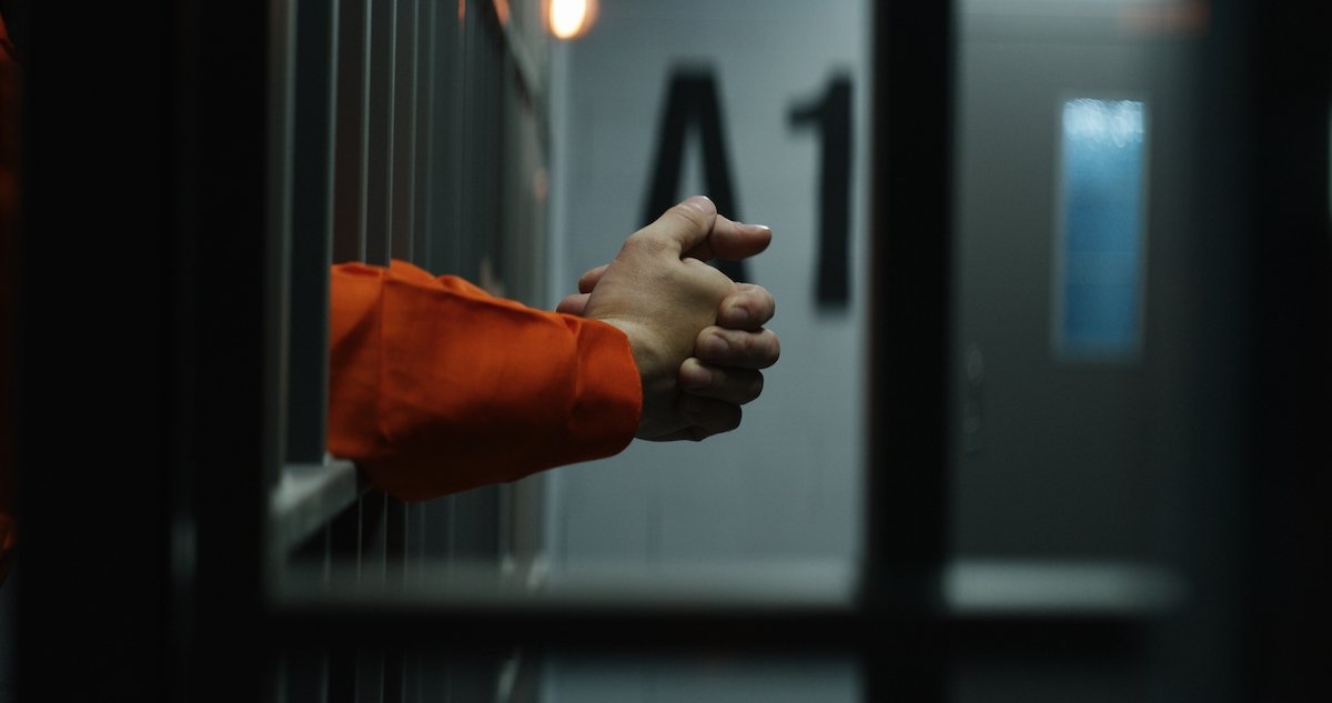 Inmate's arms reaching outside of a jail cell