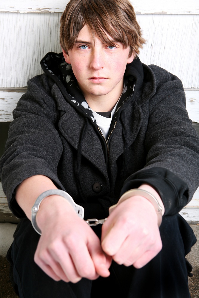 Teen boy in handcuffs - Contributing to the delinquency of a minor is a crime under Colorado CRS 18-6-701