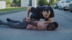 Officer arresting a man and holding him on the ground