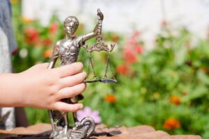 Kid's hand holding small statue of Lady Justice