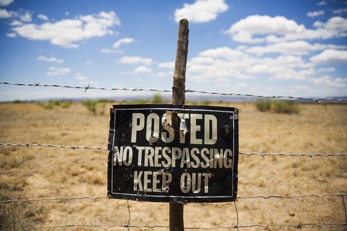 barbed wire fence and "no trespassing" sign to illustrate 1st degree trespassing per Colorado CRS 18-4-502