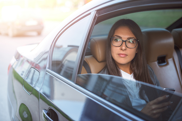 A woman traveling in the backseat of an Uber after her license got suspended from too many speeding tickets. 