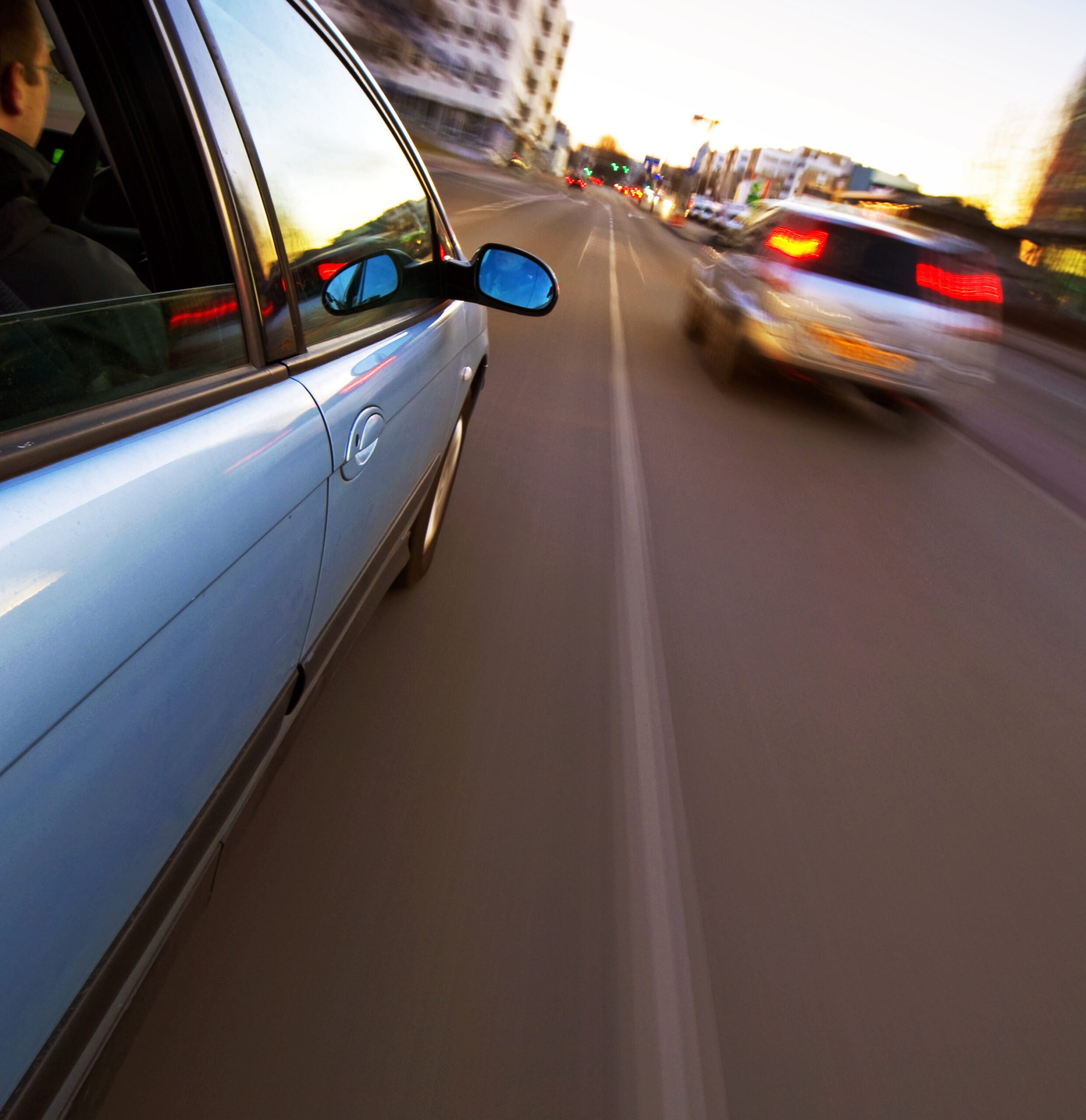 A sedan about to pass another sedan on the left hand side even though the traffic line is solid