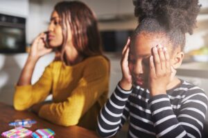 Angry parent on the phone next to a sad child