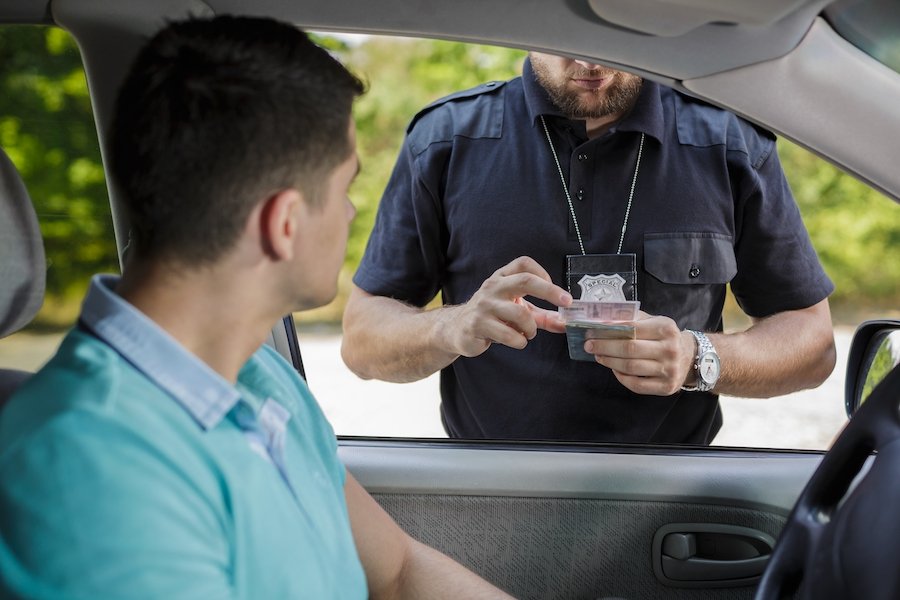 Police officer inspecting driver's license after a traffic stop