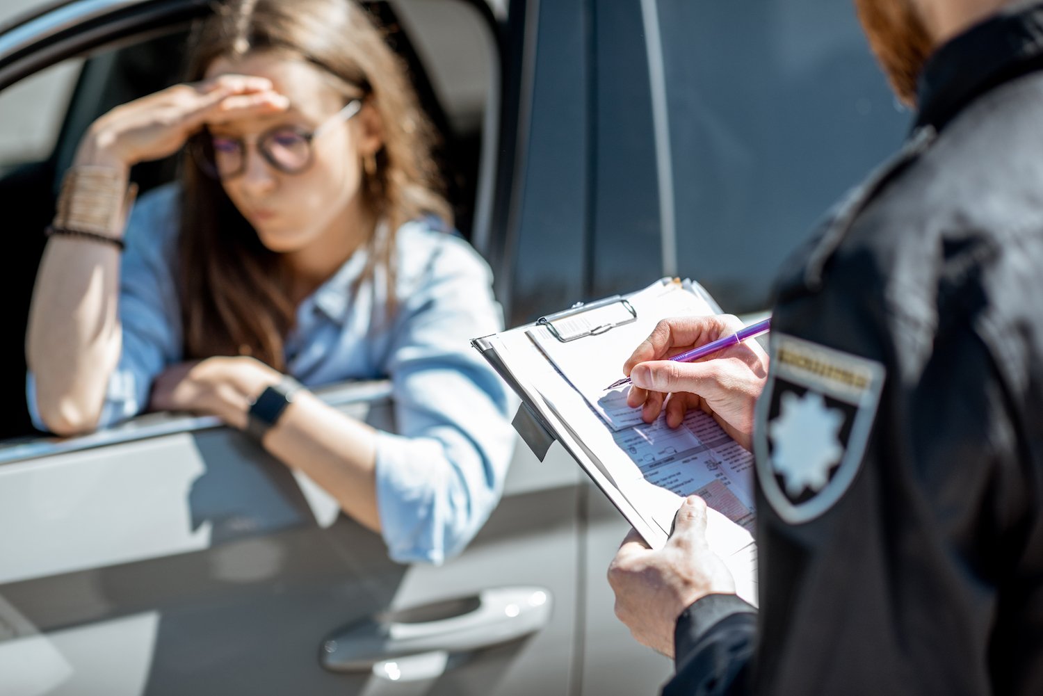 Woman driver during a traffic stop while a police officer issues her a traffic ticket