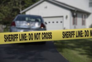 House with yellow tape that says "sheriff line: do not cross"