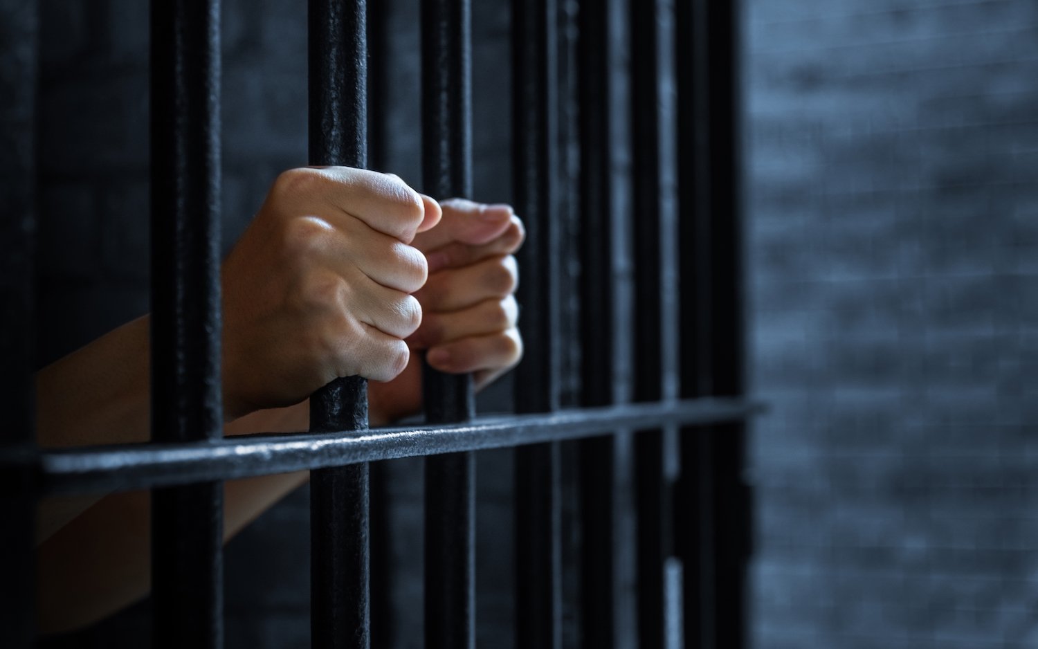 Inmate's hands gripping prison bars in Colorado 