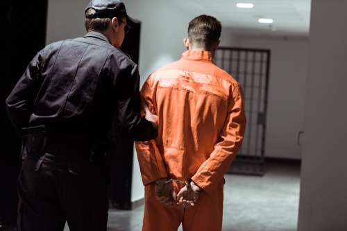 Guard walking an inmate to a jail cell.
