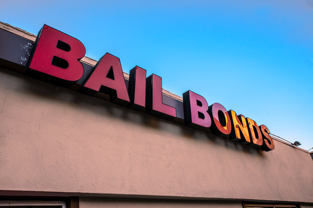 Exterior "Bail Bonds" sign above a store front against a blue sky