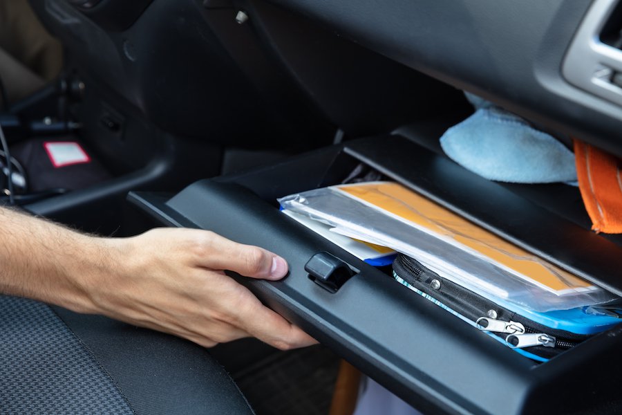 Driver's hand opening glove box to get registration out for a police officer during a traffic stop