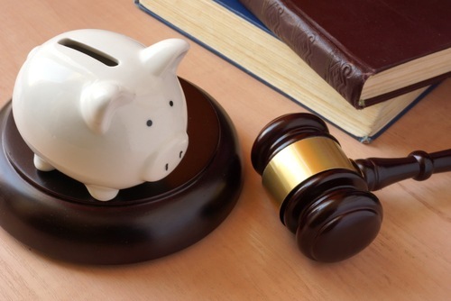A judge's gavel next to a piggy bank meant to symbolize victim restitution 