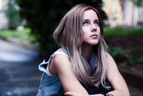 teenage girl sitting outdoors looking at the sky