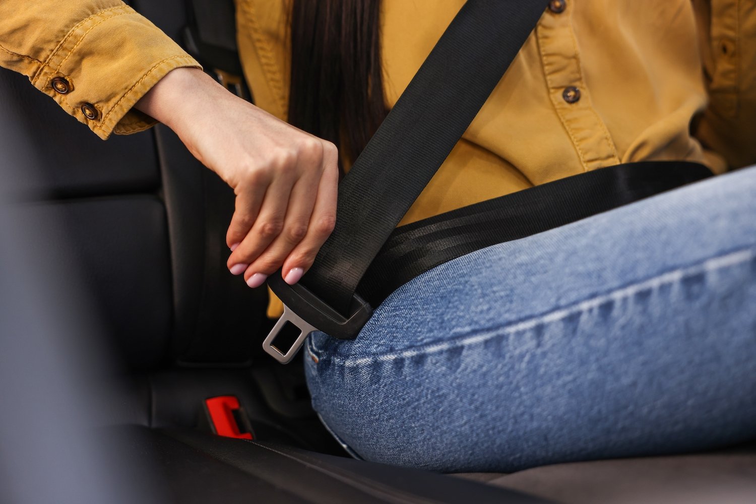 Closeup of a woman fastening her seat belt in the back seat 