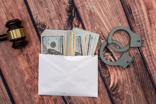 gavel, handcuffs and stack of $100 bills to illustrate money laundering in violation of CRS 18-5-309.