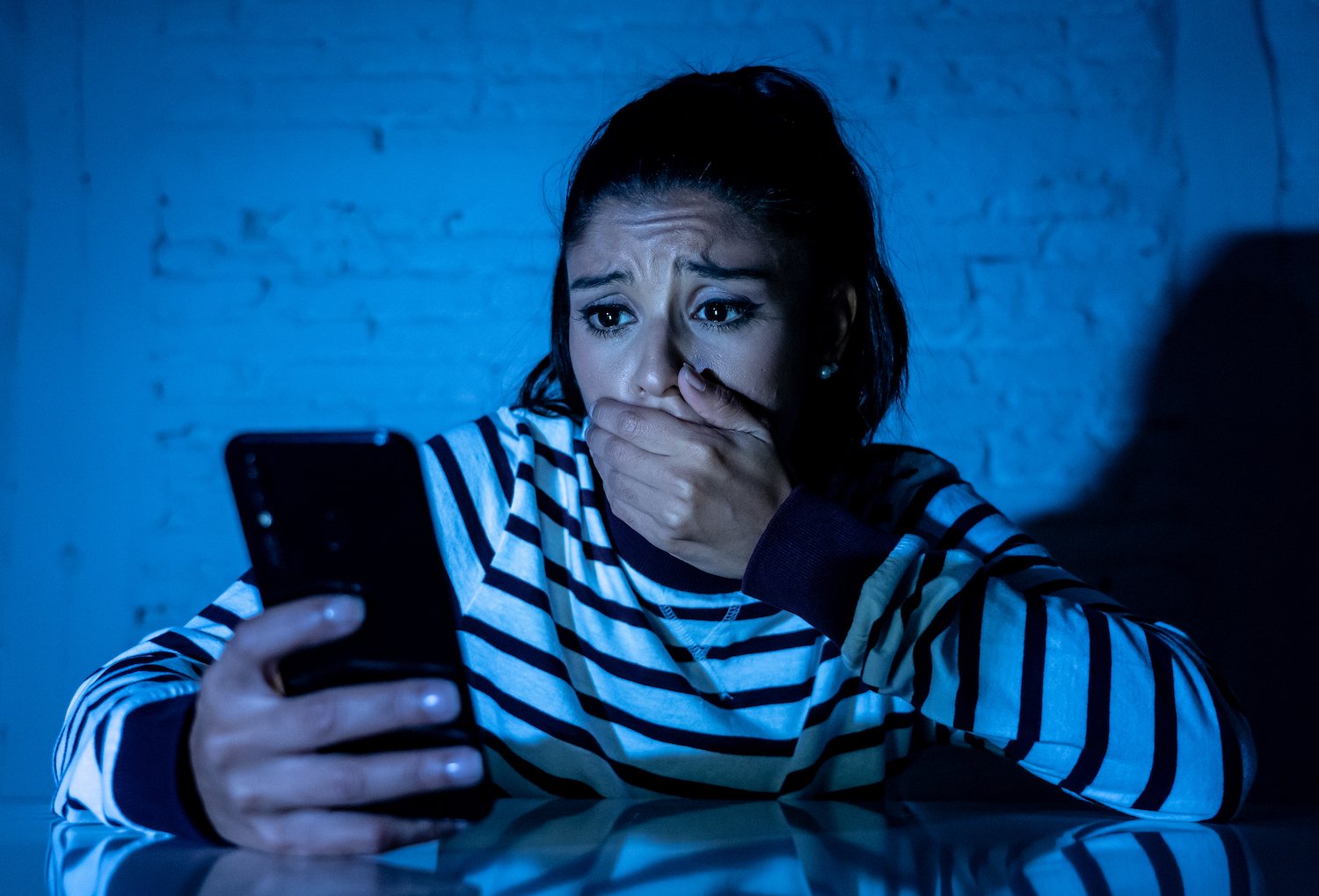 Stalker victim looking distraught after looking at her phone