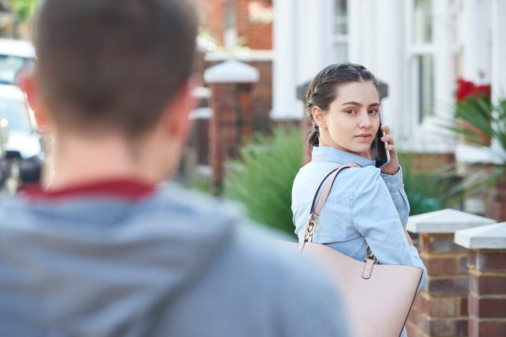 A girl noticing her ex-boyfriend stalking her in violation of CRS 18-6-803.5