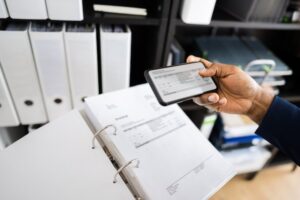 Closeup of hand holding a phone taking a photo of a trade secret