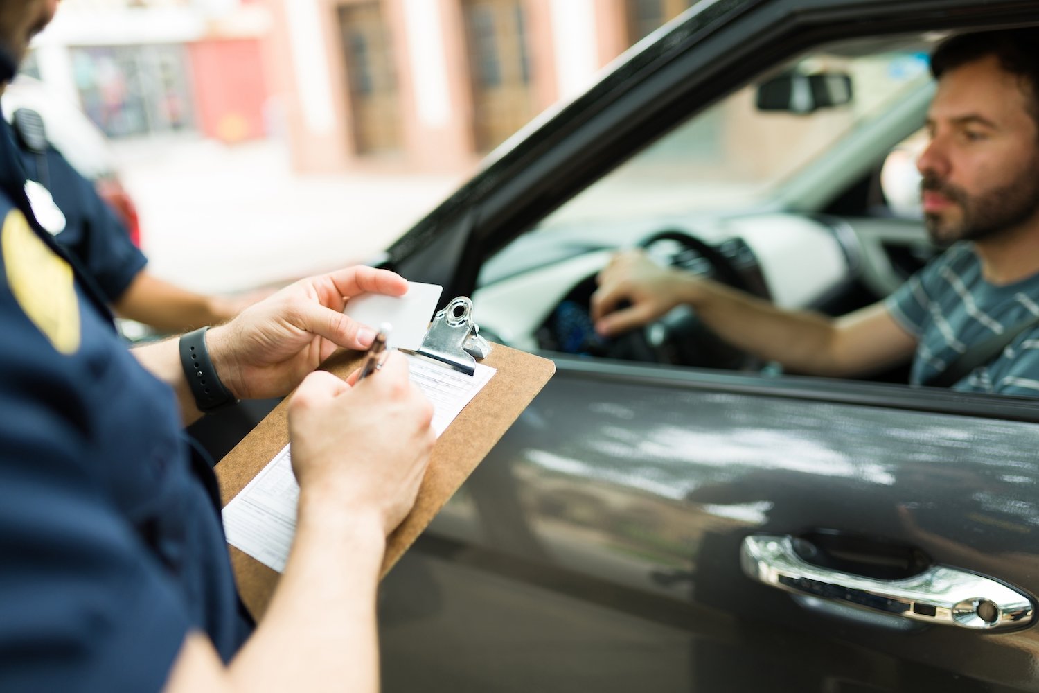 Police writing out ticket during a traffic stop, and the motorist in the passenger seat looks distressed