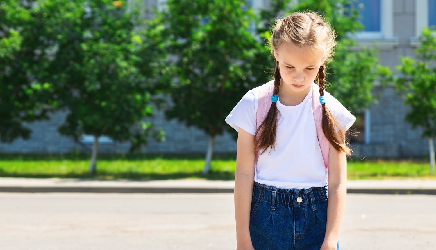 Young truant girl loitering outside of her school