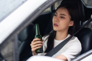 Underage driver holding a beer bottle