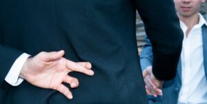 Man in suit crossing his fingers behind his back