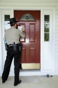 Sheriff fuera de una casa a punto de ejecutar una orden de registro.
