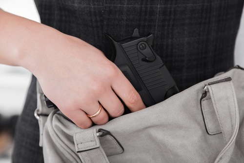 Woman hiding a gun in her purse after getting an emergency permit because her ex-boyfriend made threats. 